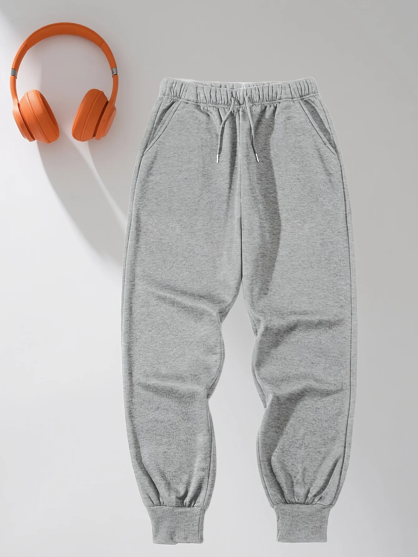 Calça de moletom casual masculina cinza folgada com punhos enrolados no tornozelo e cintura com cordão, adequada para todas as estações.