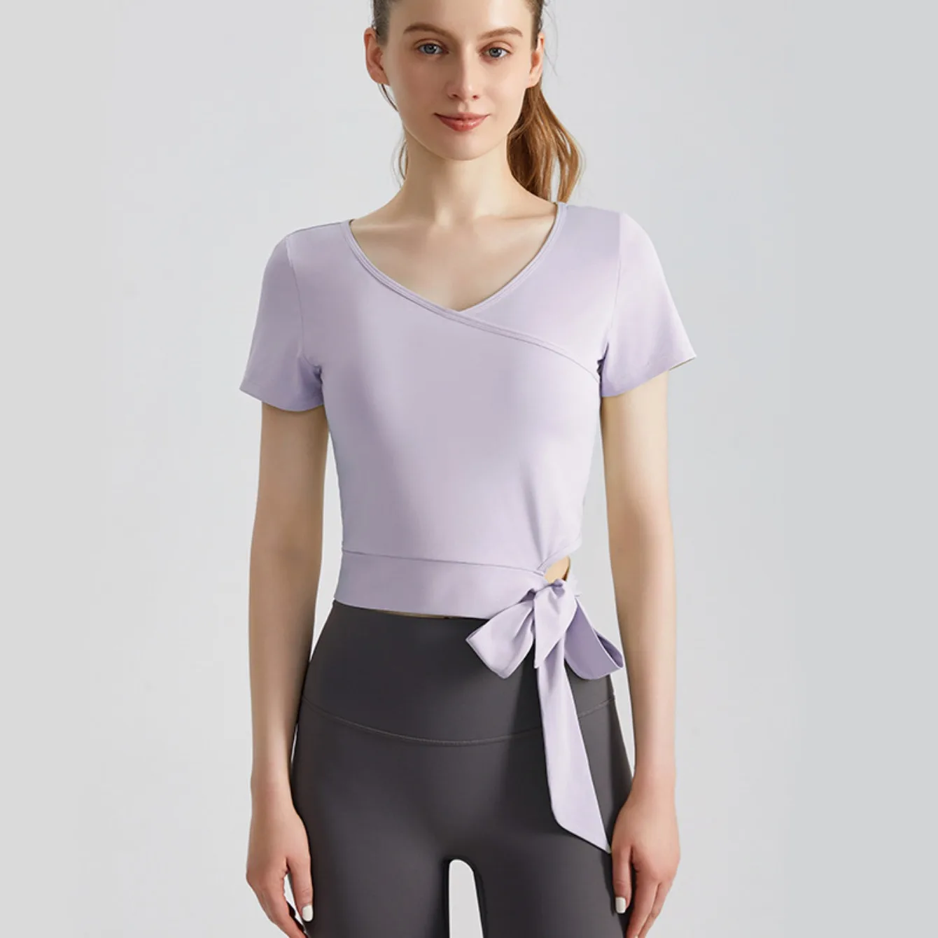 

Сухой и утягивающий топ для пилатеса и фитнеса. Стильный облегающий топ для йоги с короткими рукавами и V-образным вырезом с завязками по бокам.