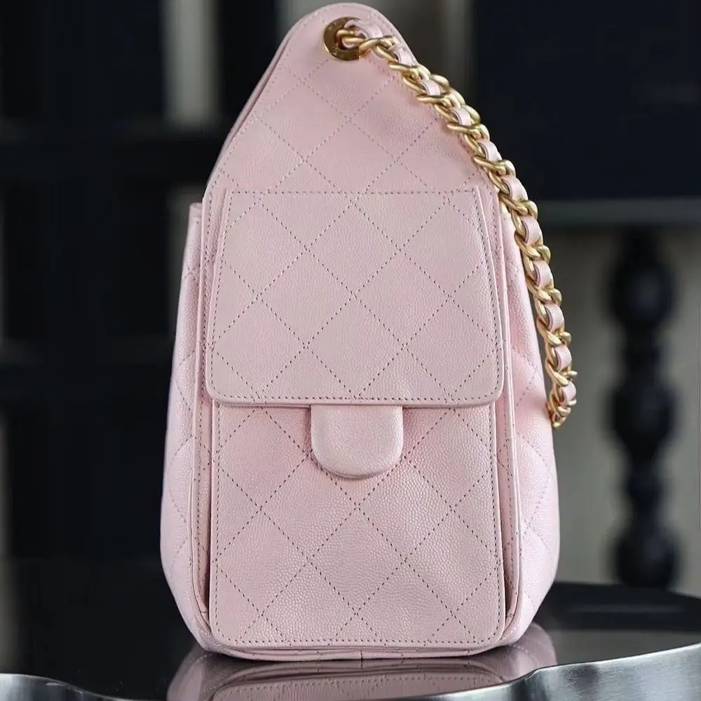 Pastel pink grainy leather drawstring bag with diamond stitching pattern, matte gold hardware, and a soft, drapey shape.