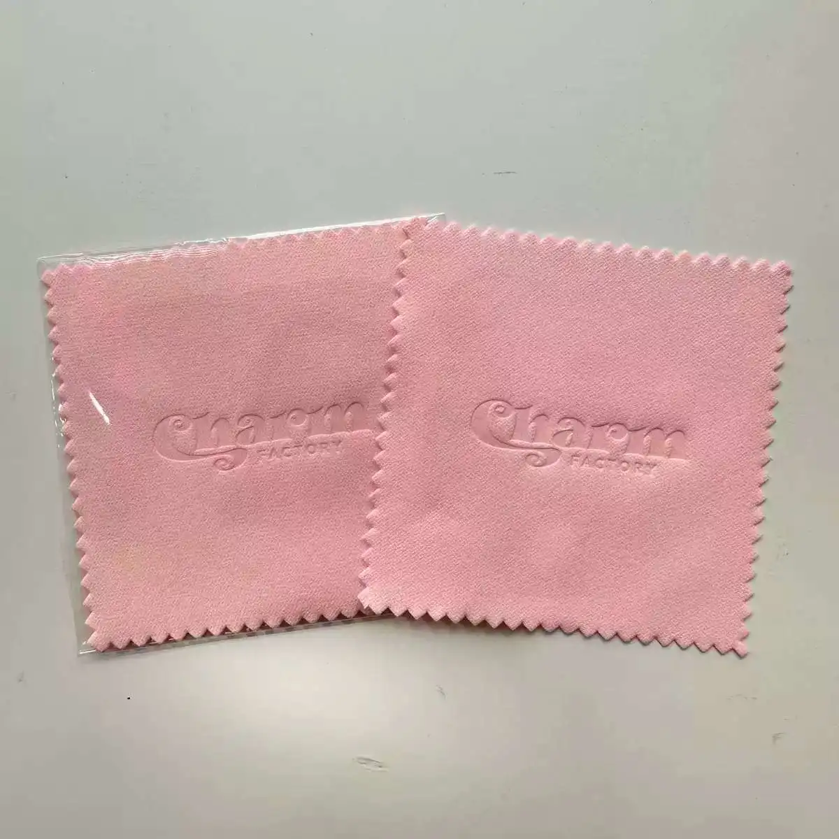 エンボス加工ロゴ入り研磨クロス。ピンク、白、スカイブルー、グレー、紫、黒のカラーからお選びいただけます。サイズはすべて対応可能。200枚から製作可能です。
