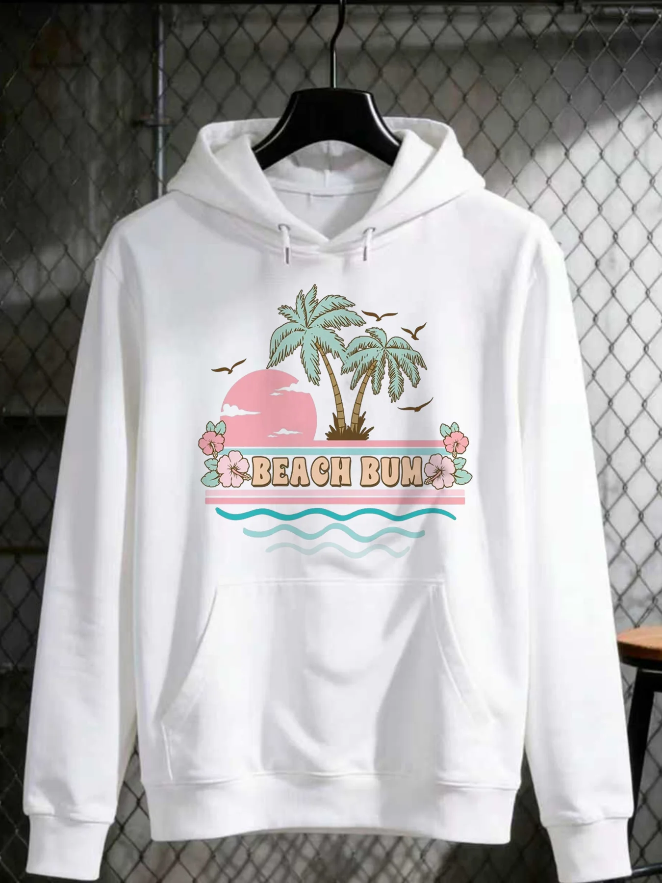 A Casual Hoodie Design Featuring a Retro Style with Palm Trees, a Pink Sunset, Birds, And Hibiscus Flowers in Pastel Colors. Perfect for Beach Lovers, It Showcases Tropical Vibes with Waves on a White Background