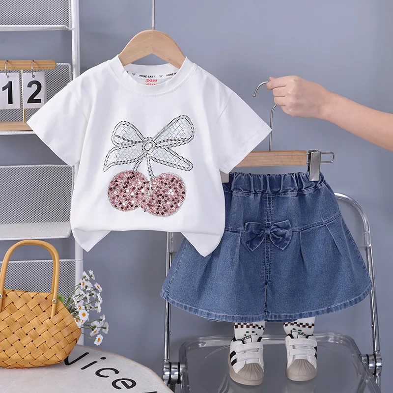 

Летний комплект для девочек 2026: Новые футболки с пайетками и вишневым бантом и джинсовые шорты-юбки, 2 предмета, милый повседневный наряд для малышей