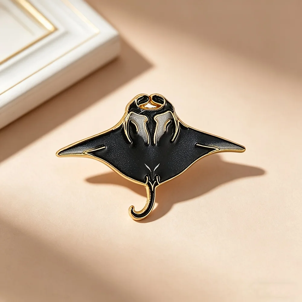 A single black and gold manta ray enamel brooch—a marine-themed accessory that pairs perfectly with denim jackets and backpacks