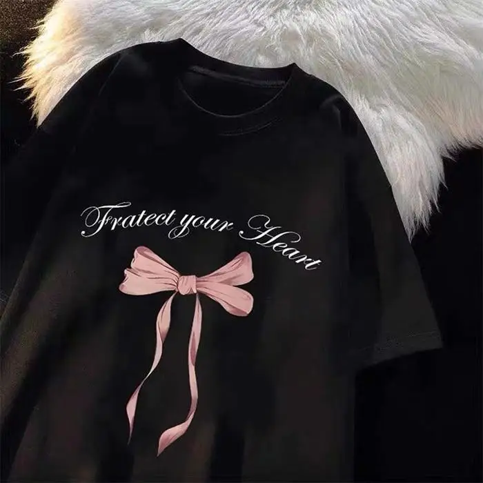 

Черная футболка: дизайн «Защити своё сердце» с розовым бантом. Графические футболки, летняя уличная одежда, женская одежда, модная эстетика.