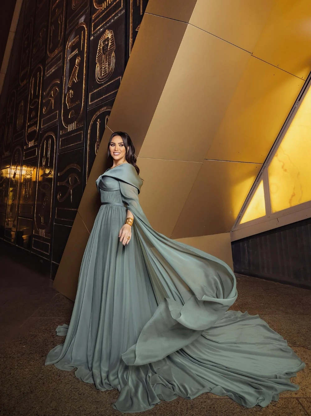 ชุดราตรีสไตล์อียิปต์โบราณสีเขียวอมฟ้า แขนเคป จับจีบ สง่างาม แบบอาหรับ พร้อมชายกระโปรงยาวแบบดราม่า สามารถสั่งตัดได้