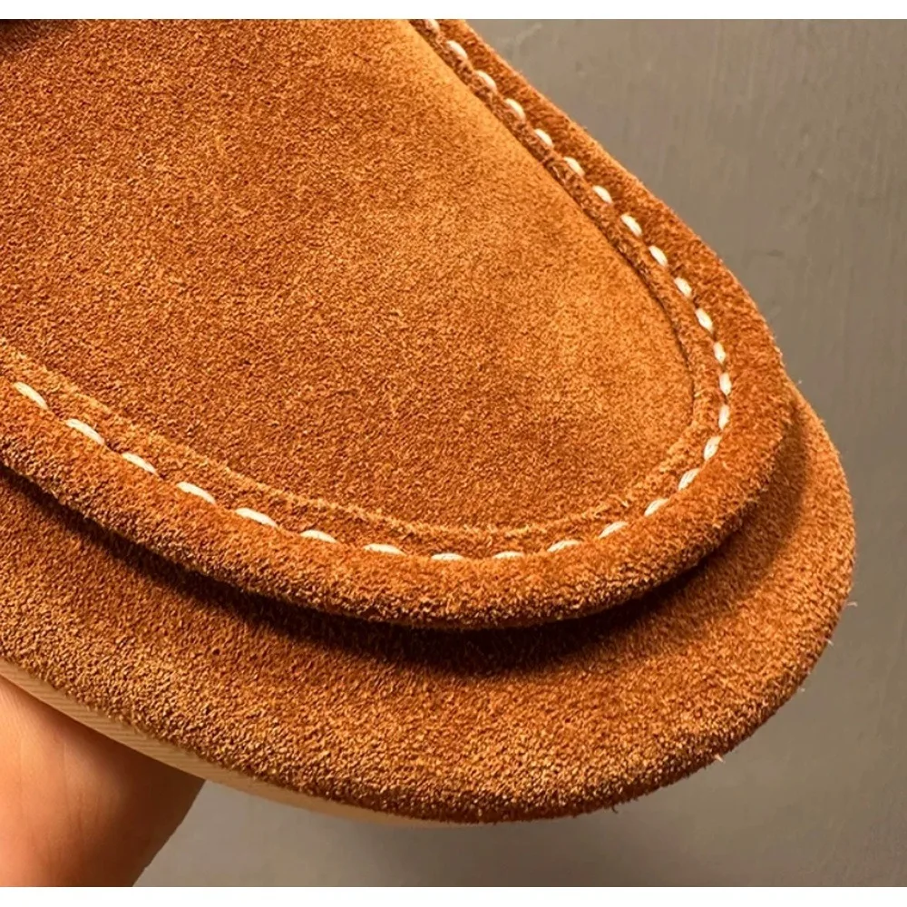 Men's brownish-yellow suede loafers, hand-stitched with a flat sole for a casual style.