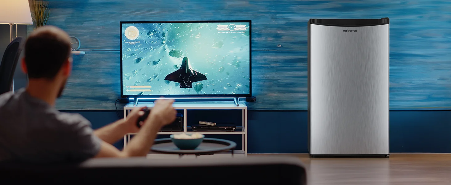 Person, die auf einem großen Flachbildfernseher eine Unterwasserszene mit Flugzeugen zeigt. Silbernes Gerät, möglicherweise Kühlschrank oder Luftreiniger, rechts neben dem Fernseher sichtbar