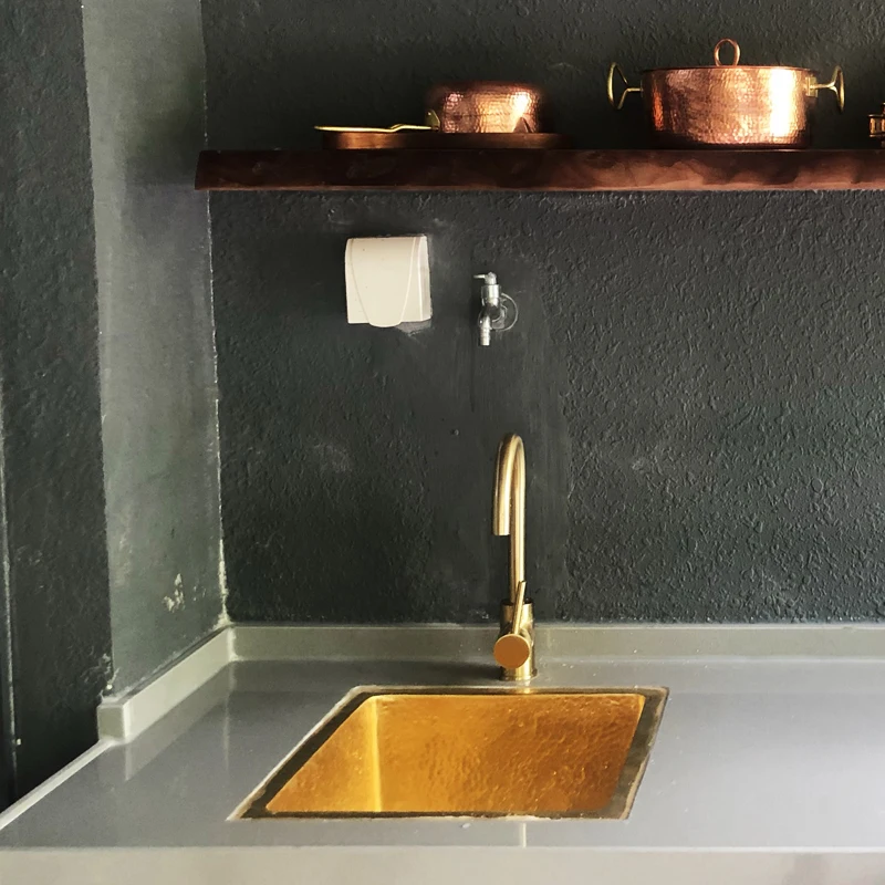 French retro kitchen with large single sink embedded in island countertop, water bar, sink, pure copper and gold basin