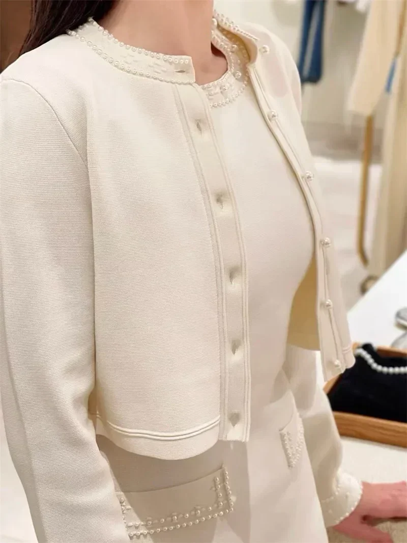 

Женский бежевый вязаный костюм-двойка, кардиган с длинными рукавами и круглым вырезом или платье-жилет без рукавов.