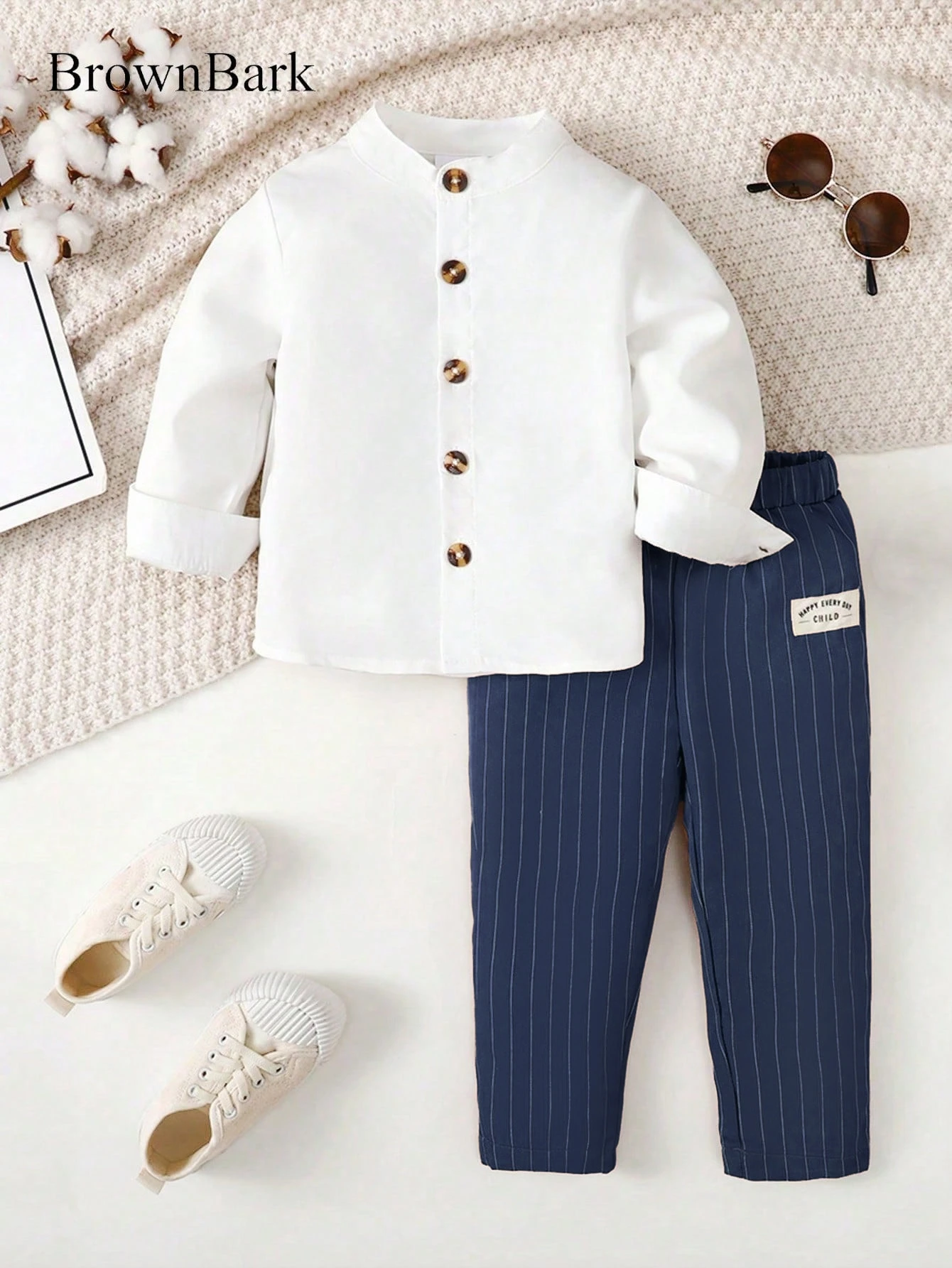 Conjunto de dos piezas de manga larga a la moda para niños, con un sencillo cuello alto y una camisa blanca de un solo botón combinada con pantalones azul marino con rayas verticales, con delicadas decoraciones de tela