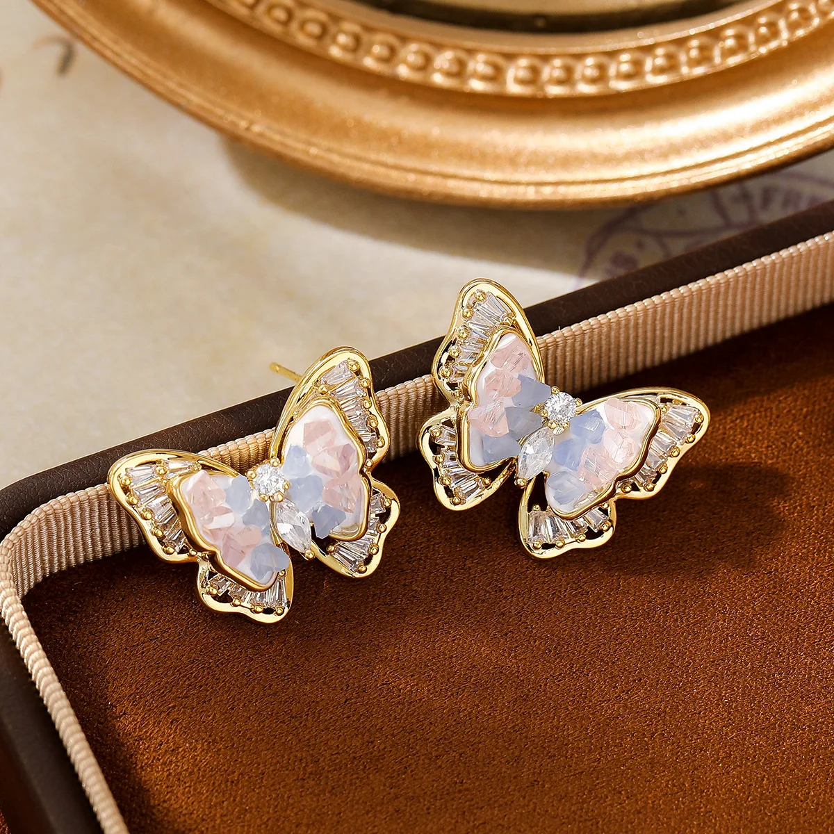 Gradually changing blue-pink crystal butterfly stud earrings with tiny inlaid diamonds as the ear jewelry.