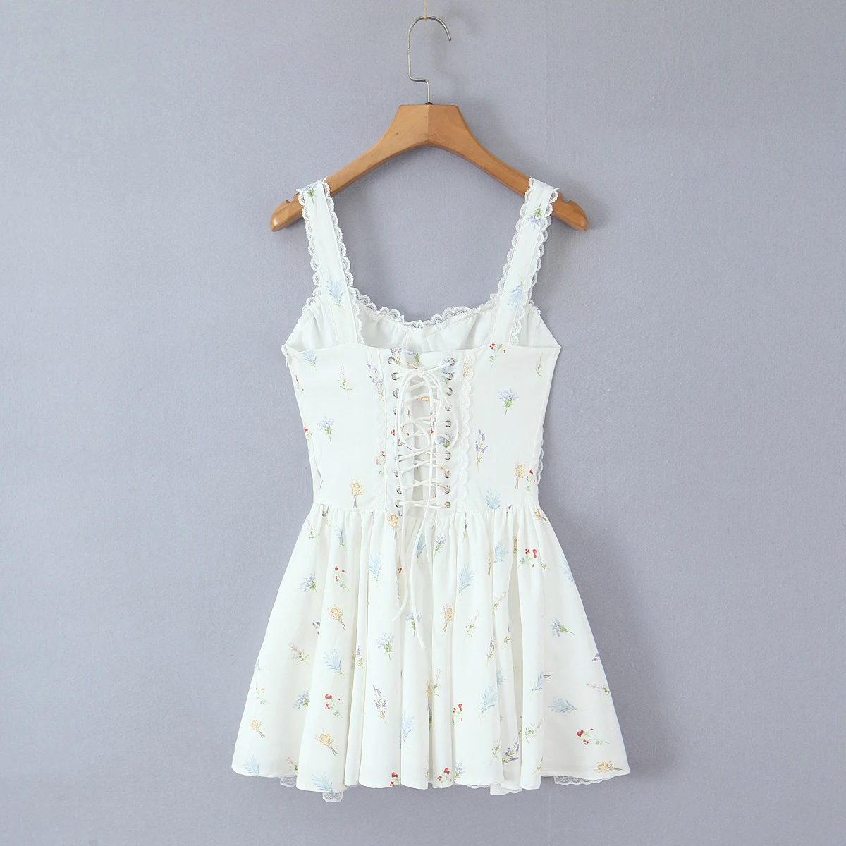 甘い花柄プリントとレースを組み合わせた、胸元にギャザーが入ったミニ丈のスリングドレス。女性用、クロスバックで紐を結ぶ、ローウエストのAラインスイングタンクドレス。