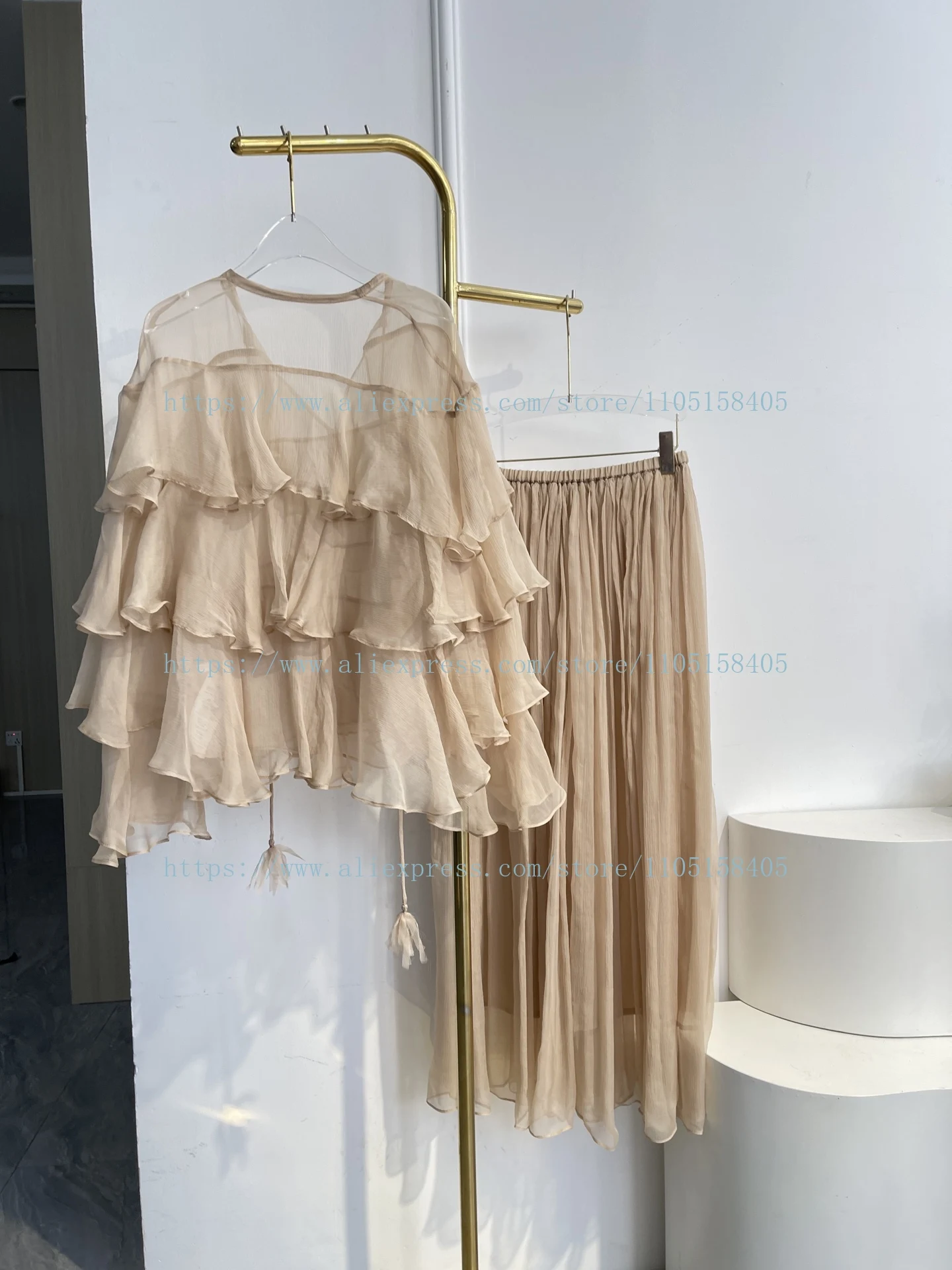 

Элегантный комплект 2026: блузка с длинным рукавом, оборками и каскадными элементами, и юбка миди в нюдовых тонах для женщин