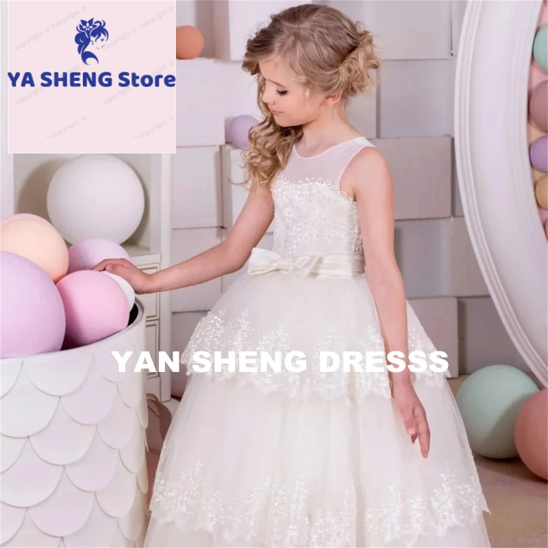 فساتين فتاة الزهور المخصصة من التل العاجي والتطريز بالدانتيل مع حزام فيونكة بدون أكمام لحفلات الزفاف وأعياد الميلاد والتواصل المقدس