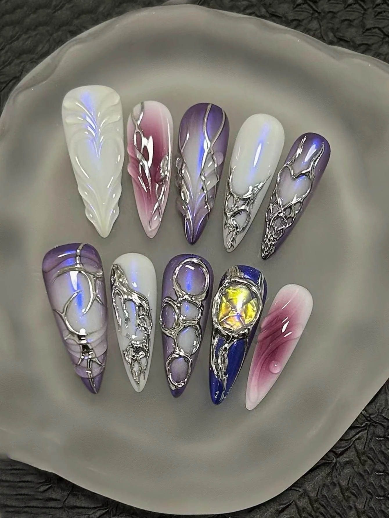 Set of 10 handmade press-on nails; long stiletto shape; featuring a handmade iridescent purple finish, 3D silver openwork metal