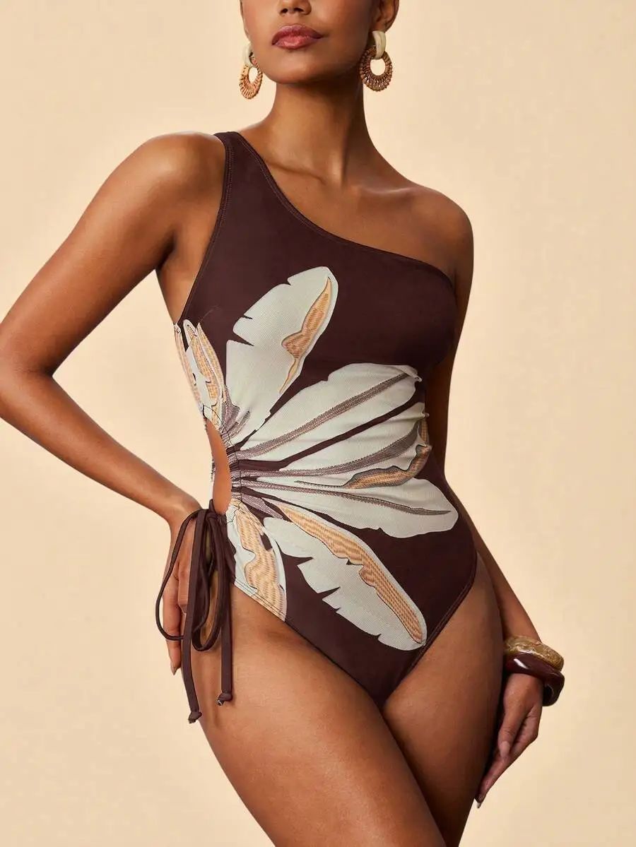 

Brown One-Piece Swimsuit Featuring Large Floral Graphic, Asymmetrical Neckline, And Adjustable Side Tie Waist