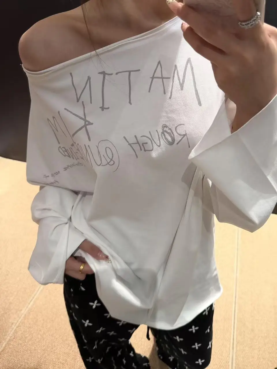 MATIN KIM Graffiti‑Letter Print Long‑Sleeve T‑Shirt, Loose Asymmetrical One‑Shoulder Top Korean Streetwear for Spring Autumn