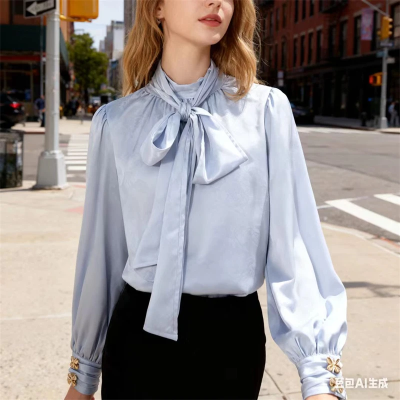 بلوزة نسائية من الساتان باللون الأزرق الفاتح مع ربطة عنق وأساور زهور ذهبية، قميص مكتب أنيق بأكمام طويلة منتفخة