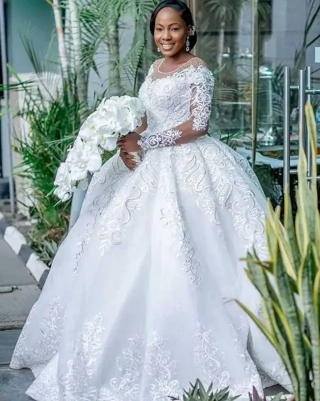 فساتين زفاف مخصصة مقاس كبير 2025 فاخرة بأكمام طويلة مزينة بالدانتيل مطرز برقبة شفافة أفريقية فستان زفاف الأميرة