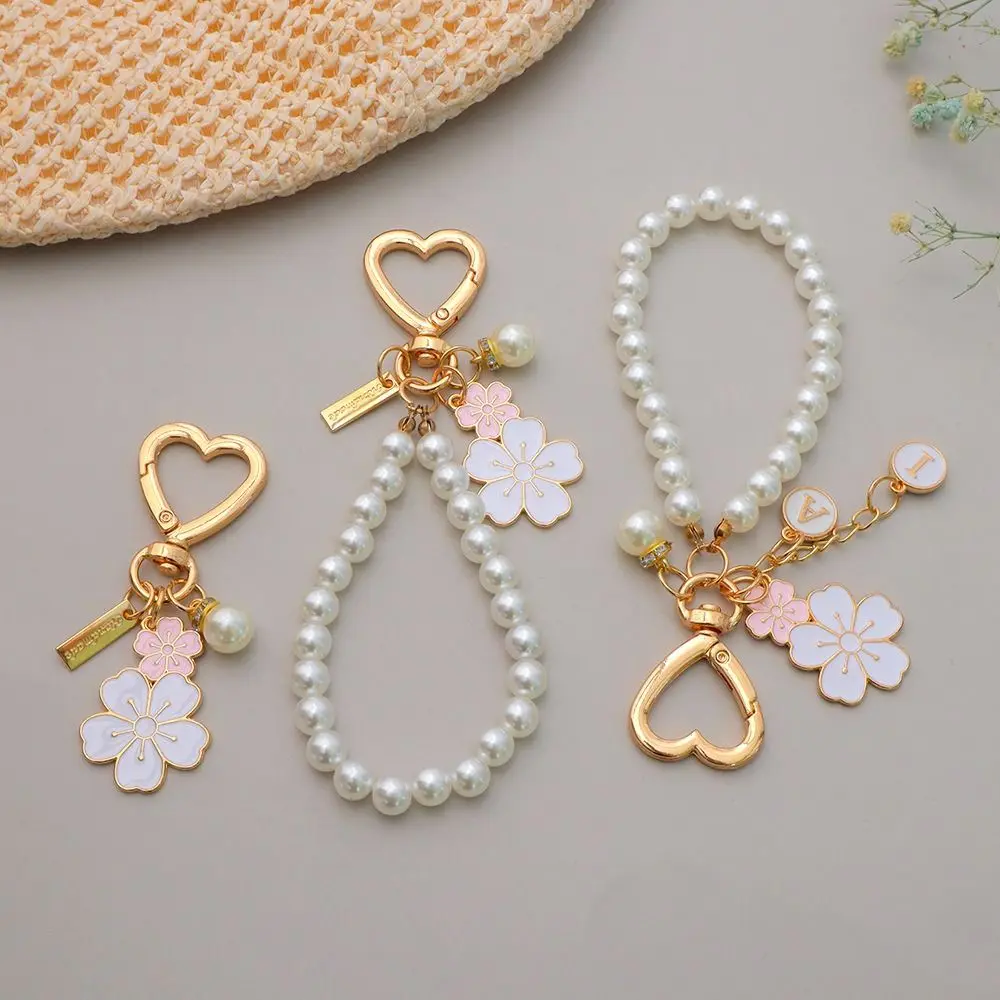 LLavero de flores de cerezo con colgante de letras a la moda, cadena con cuentas de perlas a la moda, funda para auriculares, dijes, accesorios para bolso