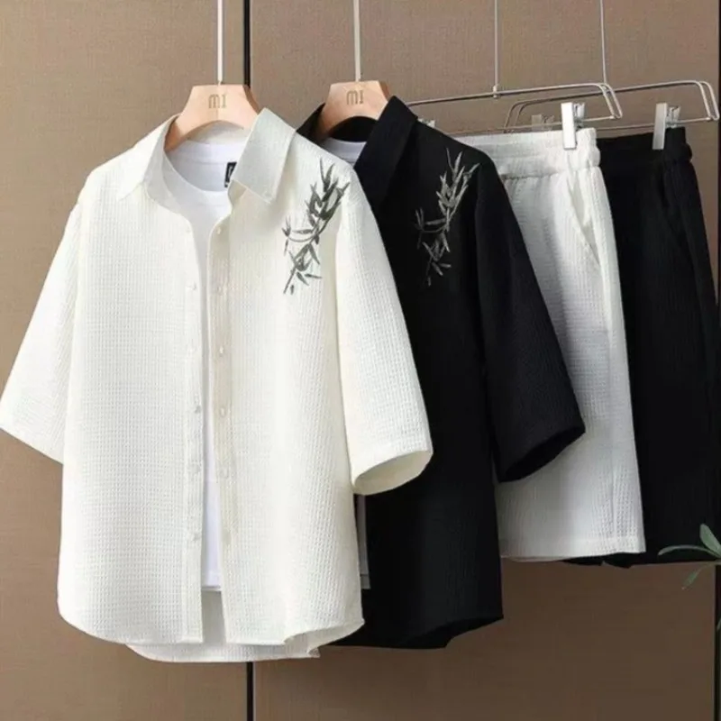 

Летний модный мужской комплект из двух предметов: рубашка с коротким рукавом из вафельной ткани свободного кроя с вышивкой в японском стиле (бамбуковые листья) и драпировкой, создающая элегантный образ