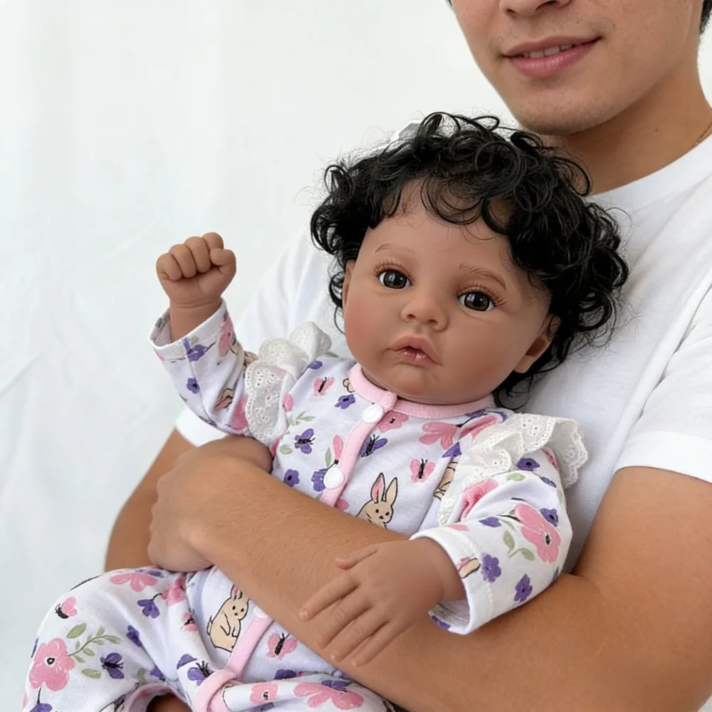 دمية طفلة رضيعة من الفينيل بطول 18 بوصة (45 سم) تشبه الطفل الحقيقي، تدعى ميدو، ببشرة داكنة، تشبه الفتيات الأمريكيات من أصل أفريقي، بشعر أسود مجعد.