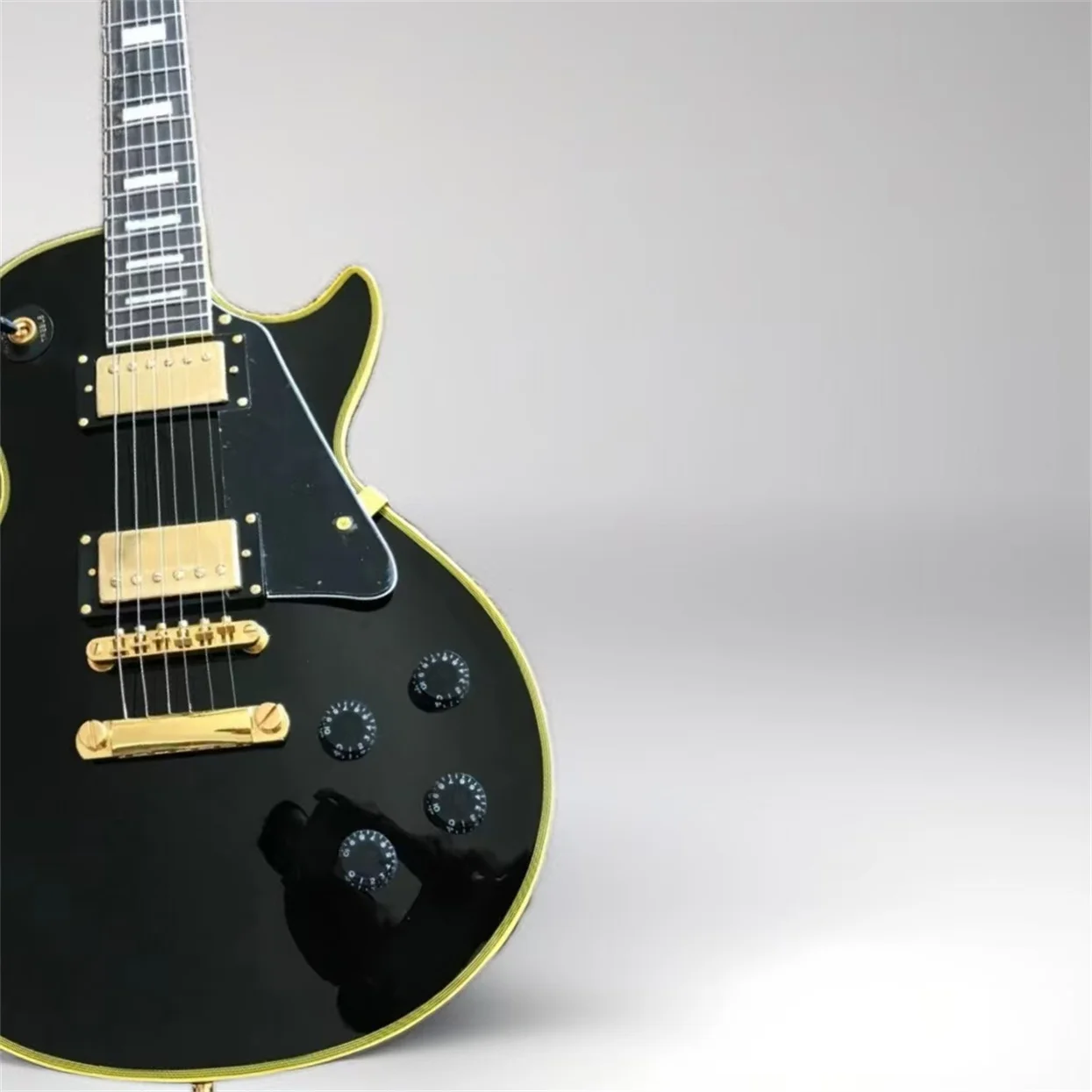 Customized electric guitar, black caston, yellow logo and body binding, gold accessories,