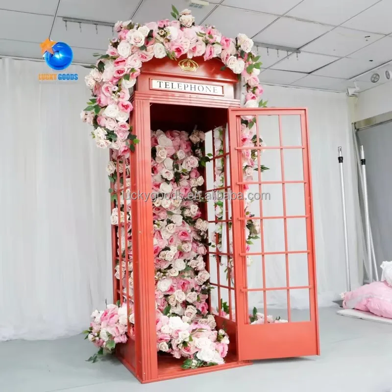 

Композиция из розовых цветов и красная металлическая телефонная будка для декора торгового центра