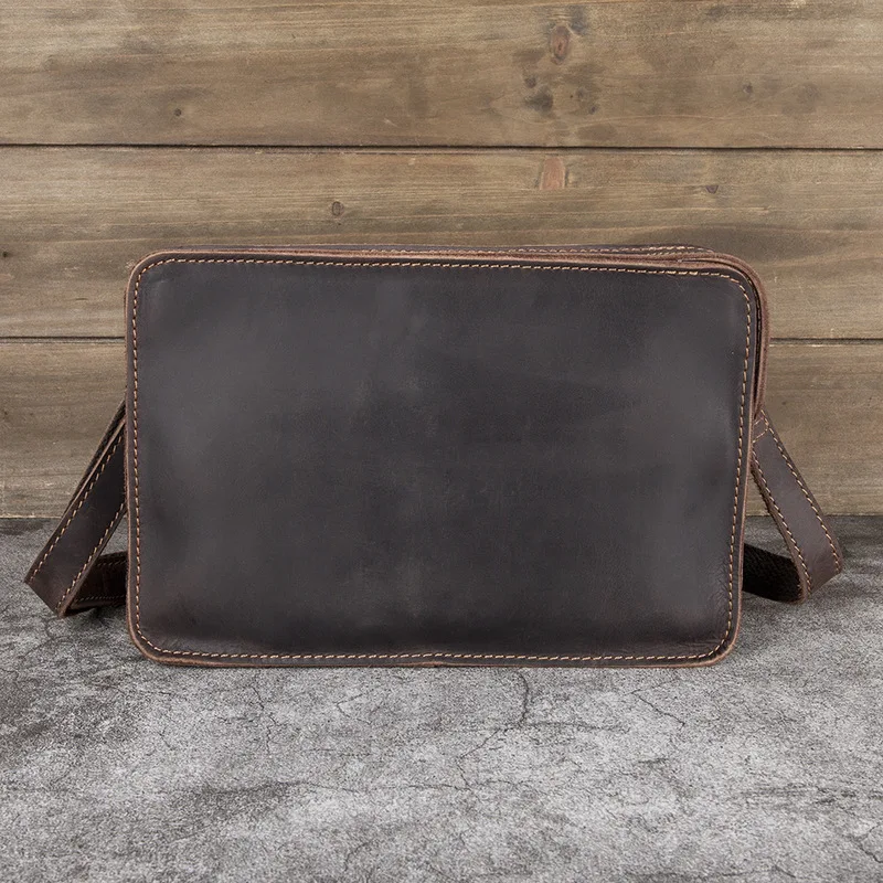 The man is holding a leather small crossbody bag. It is made of top-grade cowhide and features a retro hand-held design.