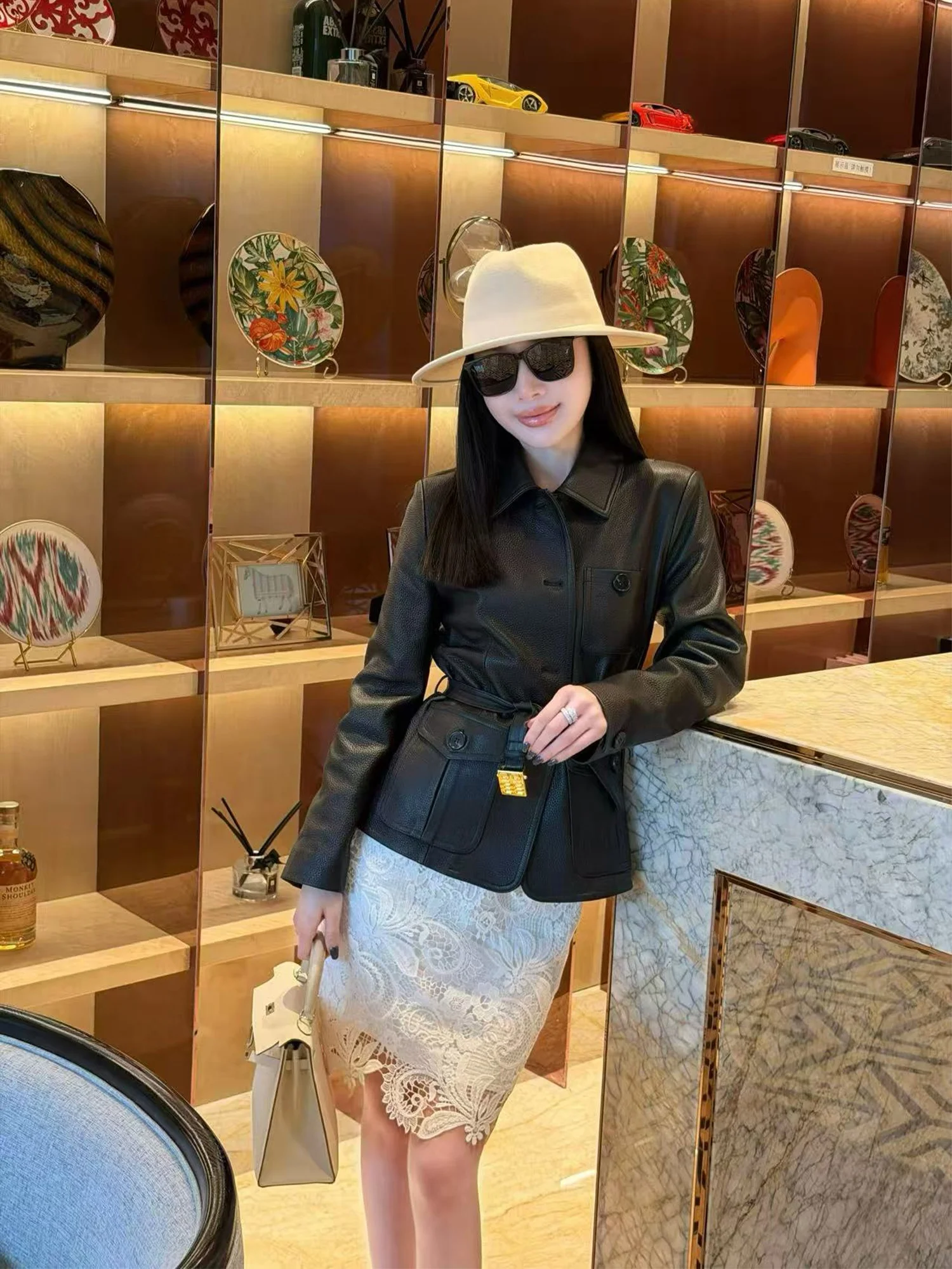 

Стильная женская кожаная куртка из овчины черного цвета с поясом, современный фасон с завышенной талией, длинный рукав, без мехового воротника, эстетичный дизайн.