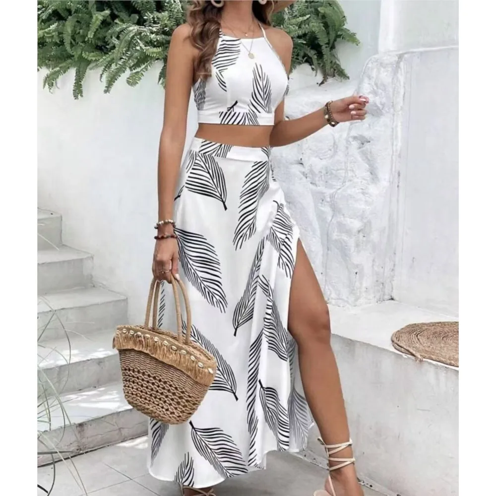 

Модный элегантный комплект из двух предметов: топ без рукавов на бретелях и короткая юбка с разрезом. Новинка лета для женщин.