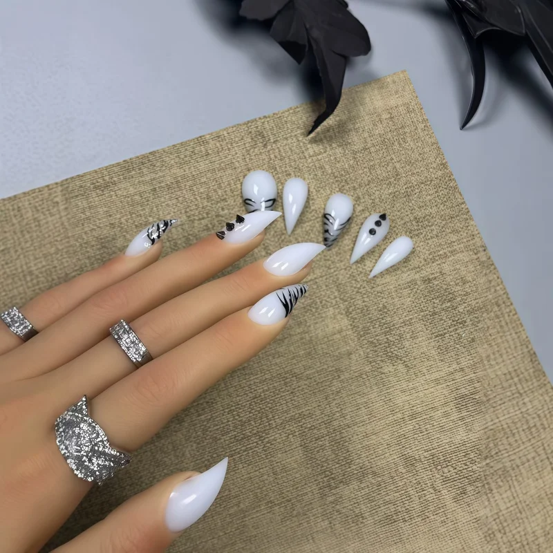 10PCS of white lacquer daggers-shaped fake nails, decorated with hand-painted abstract black ink swirl lines.