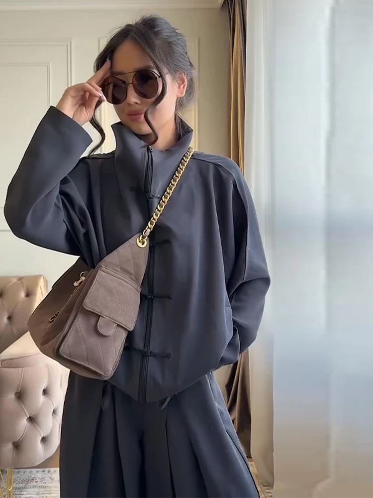 

Женский комплект из двух предметов: топ с высоким воротником на молнии и длинными рукавами с узлом и пуговицами, широкие брюки. Модный повседневный уличный стиль 2026.