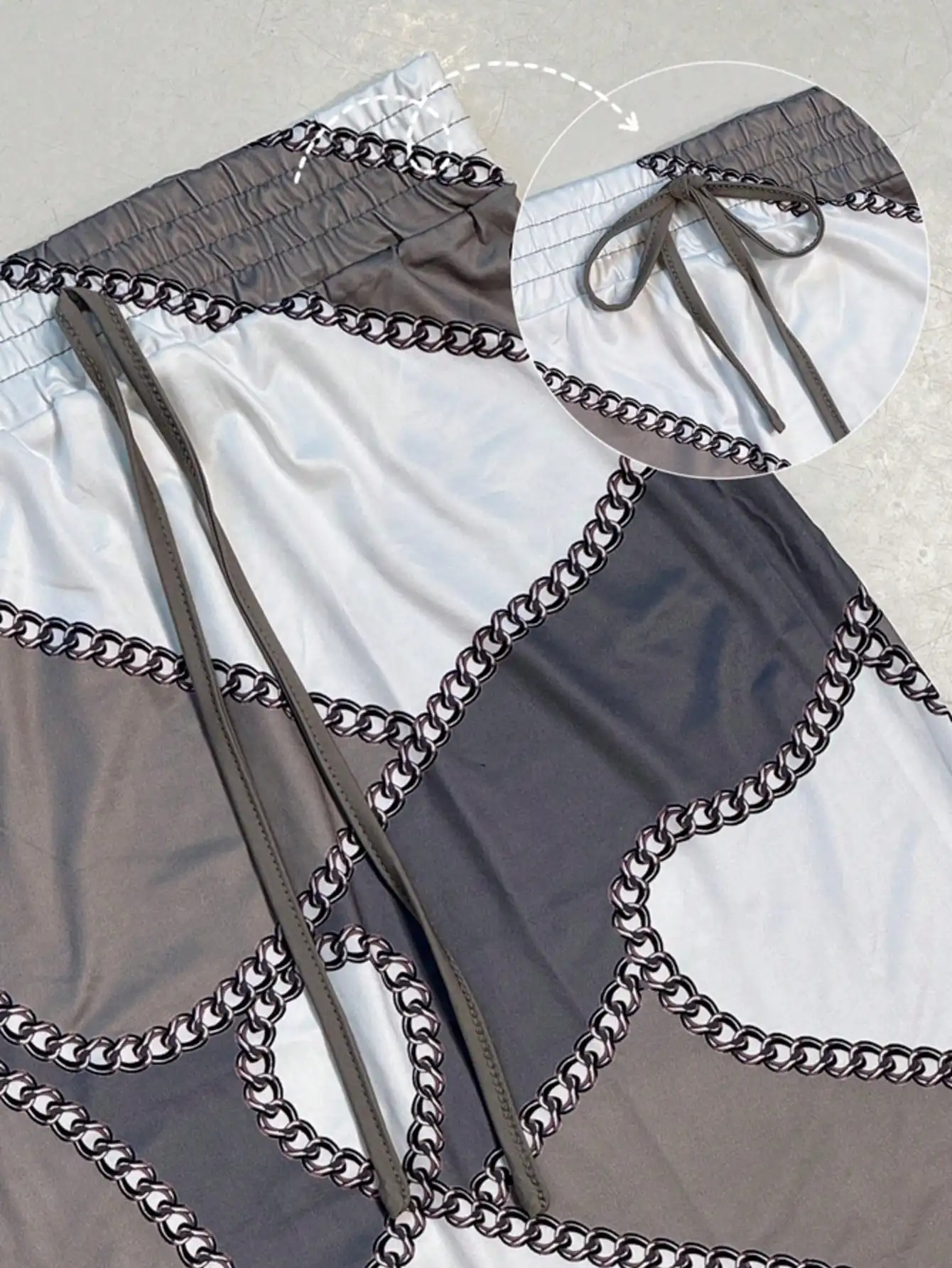 

Женский комплект из 2 предметов: укороченный топ с длинными рукавами и юбка миди с цепным принтом и цветовыми блоками, на шнурке. Элегантный повседневный офисный и уличный стиль.