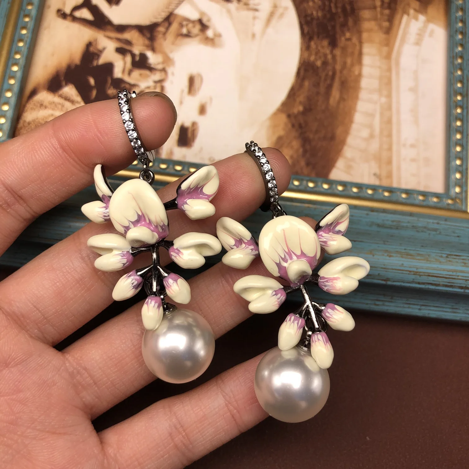 

Изысканные серьги-гвоздики с эмалью, рисунком цветов, элегантными жемчужными подвесками, свежие и изысканные.