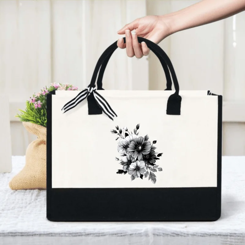Cream and black floral print canvas tote bag with ribbon detailing for everyday use and shopping.