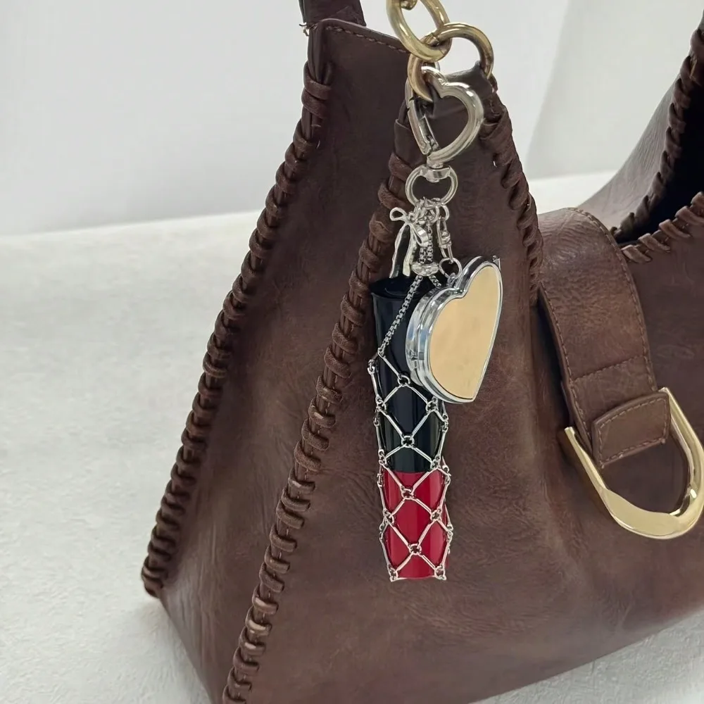 Un colgante creativo de malla con forma de lazo y espejo en forma de corazón, capaz de guardar pintalabios, auriculares y otros objetos pequeños, adecuado para decorar llaveros, bolsos, mochilas, etc. Es una excelente opción para actividades de team building corporativo y regalos para fiestas.