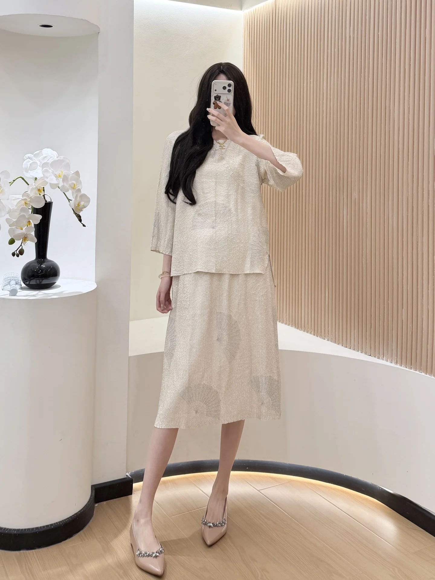 

Женский бежевый текстурированный комплект из двух предметов: топ с рукавом до локтя и юбка миди. Элегантный повседневный стиль. Модный тренд 2025 года.