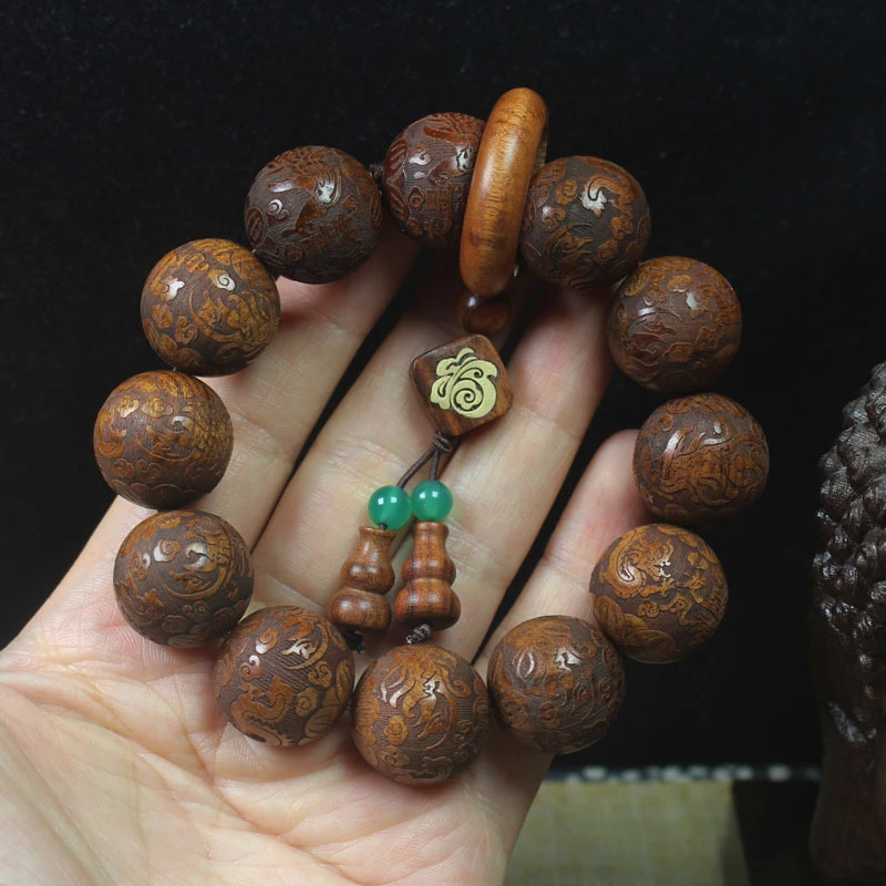 

Браслет из крупнолистового палисандра 20 мм с резными драконами и фениксами, бусинами Будды, подвеской-талисманом на удачу и молитвенной надписью.