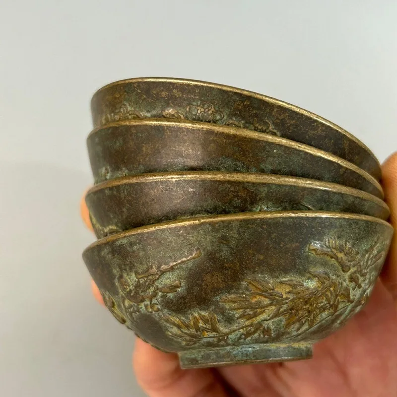 A set of copper tea bowls teacups featuring plum, orchid, chrysanthemum, and bamboo designs, a collection of artware