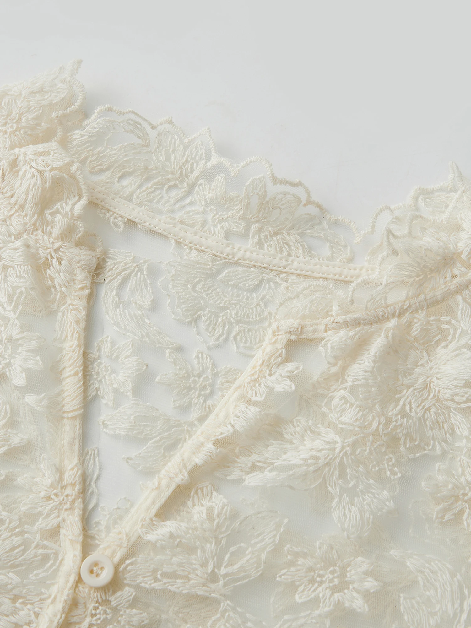 Elegancka bluzka z koronki w kwiaty z dekoltem w serek i rozkloszowanymi rękawami, idealna na imprezy robocze i wydarzenia na świeżym powietrzu.