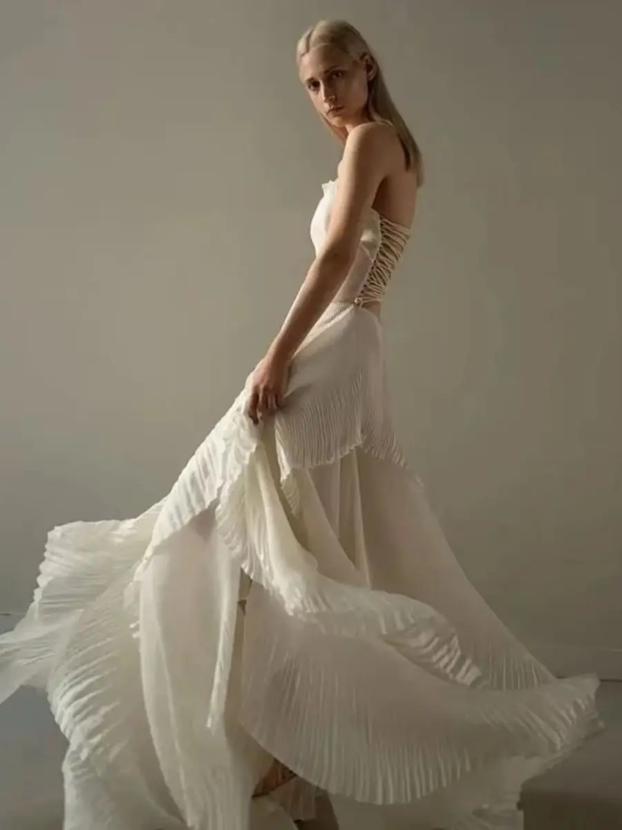 Robe de soirée maxi sans bretelles, plissée et à volants, avec corsage structuré et jupe fluide à plis superposés, idéale pour une invitée de mariage ou une cérémonie formelle.