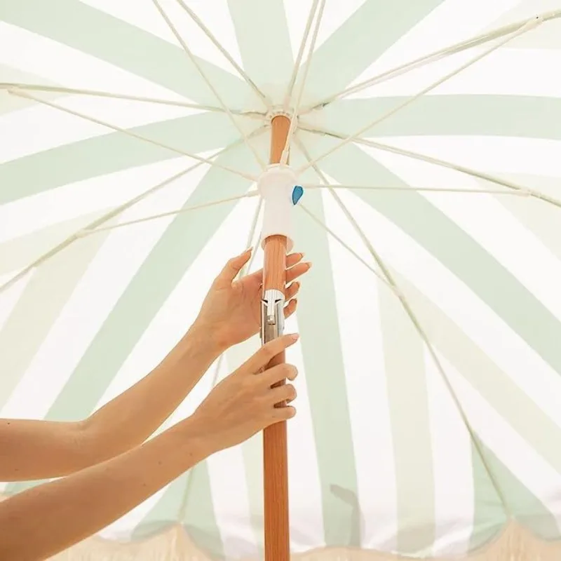 مظلة شرابة للشاطئ مخططة باللون الأخضر والأبيض والأصفر مع حماية من الشمس في الهواء الطلق