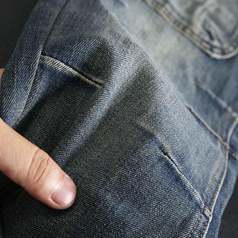 กางเกงยีนส์เย็บปะติดปะต่อสไตล์เรโทรระดับไฮเอนด์สําหรับผู้ชายที่มีกระเป๋าหลายช่อง ผ้ายืดมอเตอร์ไซค์ ทันสมัยและเข้ารูป กางเกงขาเล็ก