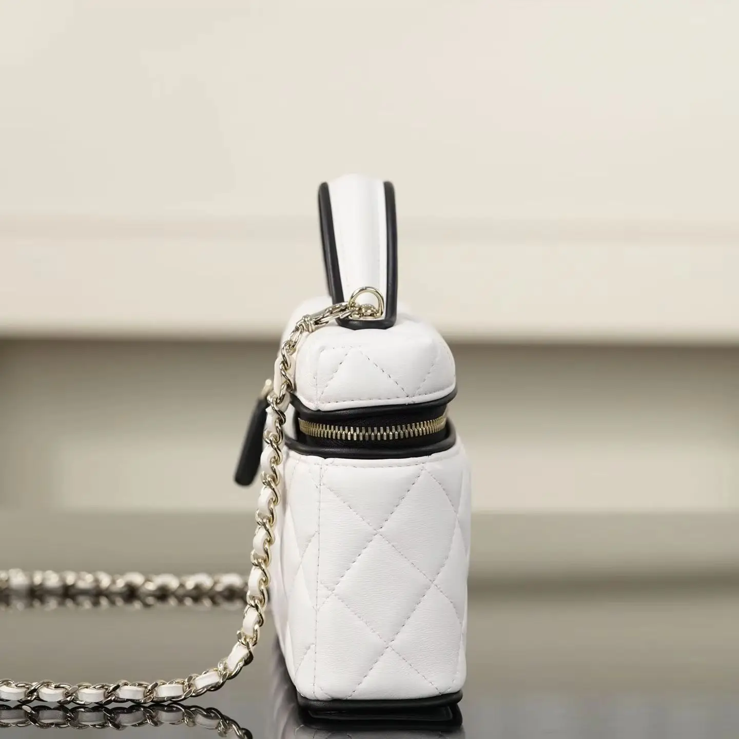 White diamond-quilted leather makeup case bag, black trim, short top handle, leather-woven silver chain shoulder strap, rectangular women's crossbody bag.