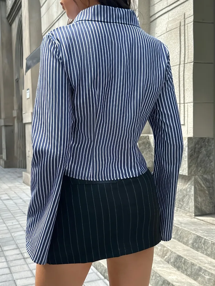 بلوزة نسائية بياقة قميص وأكمام منتفخة قصيرة بخطوط عمودية زرقاء داكنة، تصميم بسيط بأكمام واسعة قليلاً وخصر ضيق