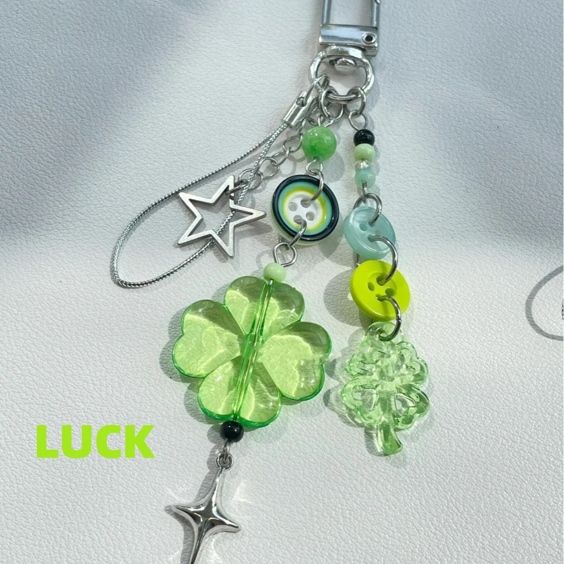 سلسلة مفاتيح صغيرة مصنوعة يدويًا بأربع أوراق البرسيم مطرزة بسلسلة كاميرا صغيرة معلقة لطيفة للهاتف المحمول