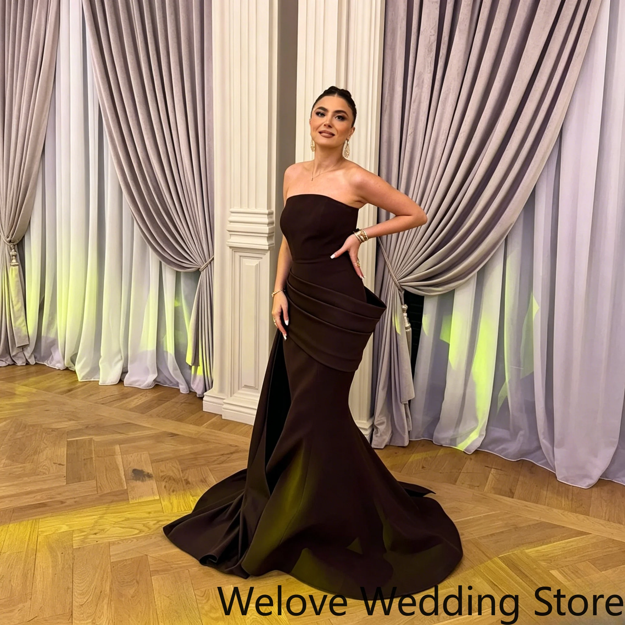 Black Formal Evening Gown Featuring a Strapless Neckline, Form-Fitting Mermaid Silhouette, and Dramatic Structured Draped Waist