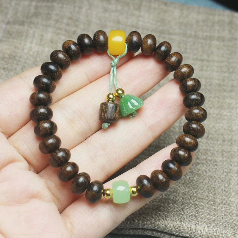 

Браслет из бусин агарового дерева с тигровым узором, маленьким кулоном в виде лотоса и буддийскими молитвенными бусинами.