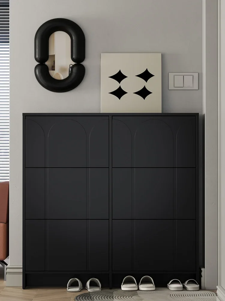 Ultra-thin shoe cabinet Narrow tipping bucket type narrow cabinet behind black door at the entrance of corridor.